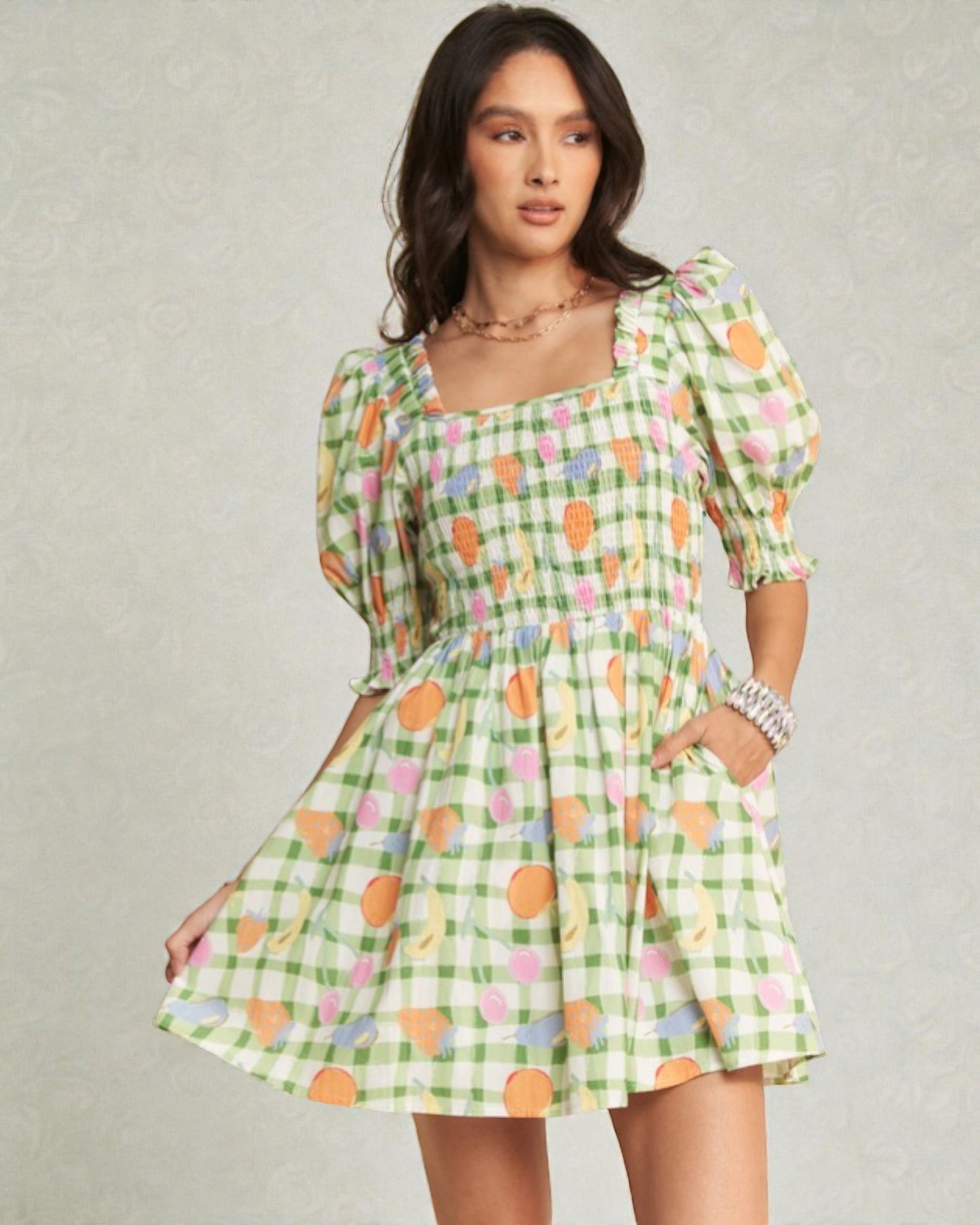 Woman wearing a green checkered dress with colorful pattern on a gray background