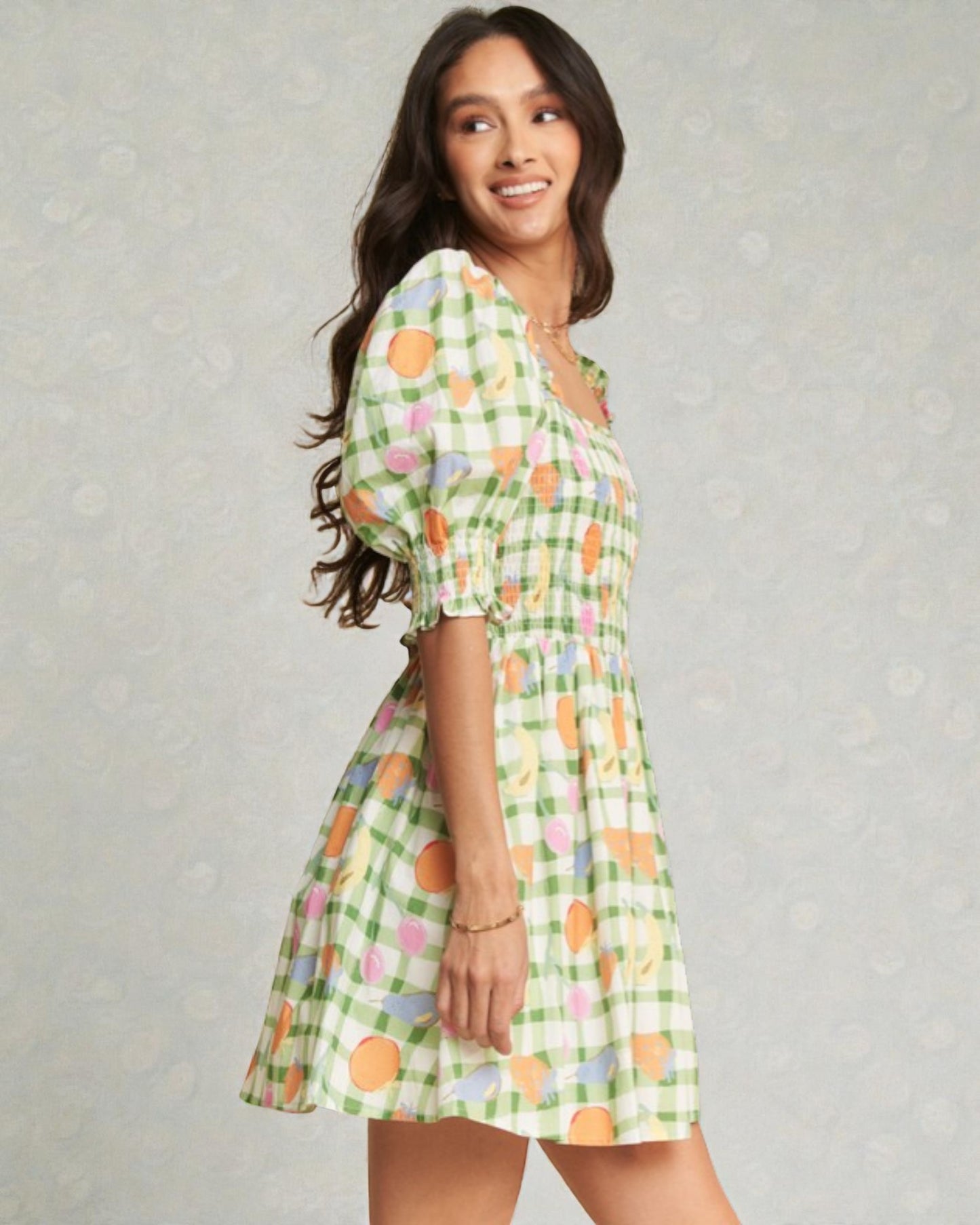 Woman wearing a green checkered dress with floral patterns on a gray background