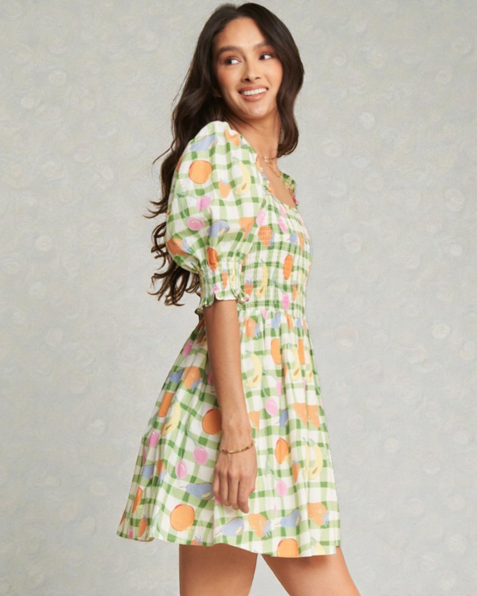 Woman wearing a green checkered dress with floral patterns on a gray background