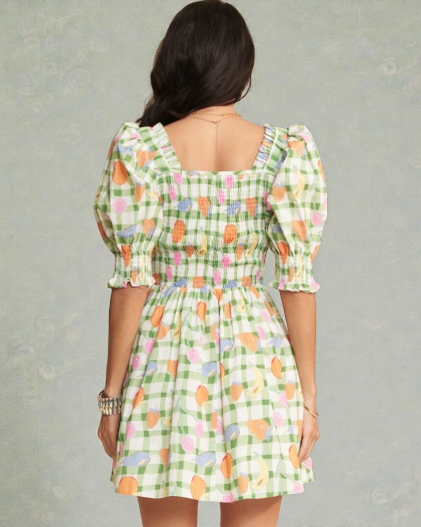 Woman wearing a green checkered dress with colorful patterns on a gray background