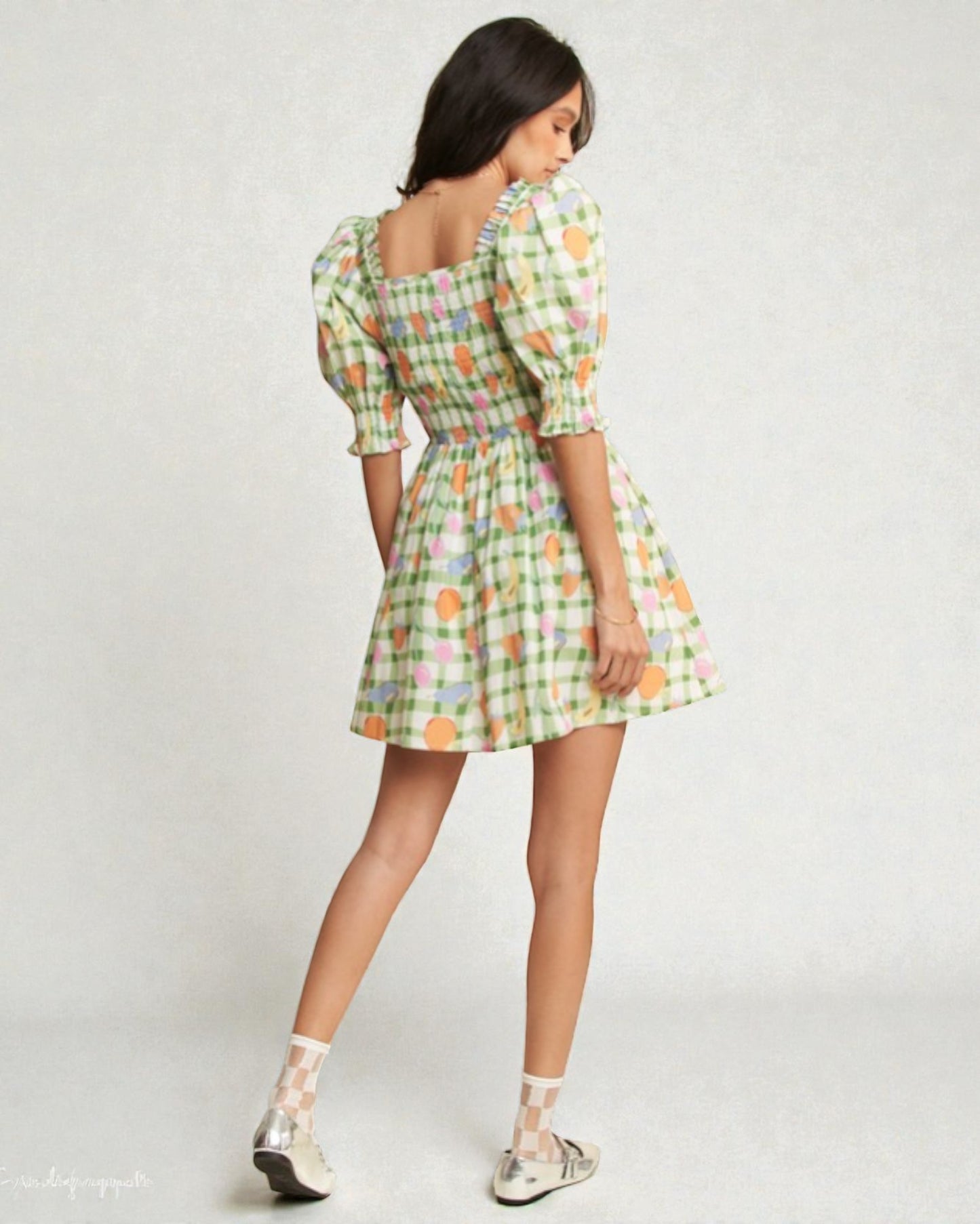 Woman wearing a colorful checkered dress on a plain background