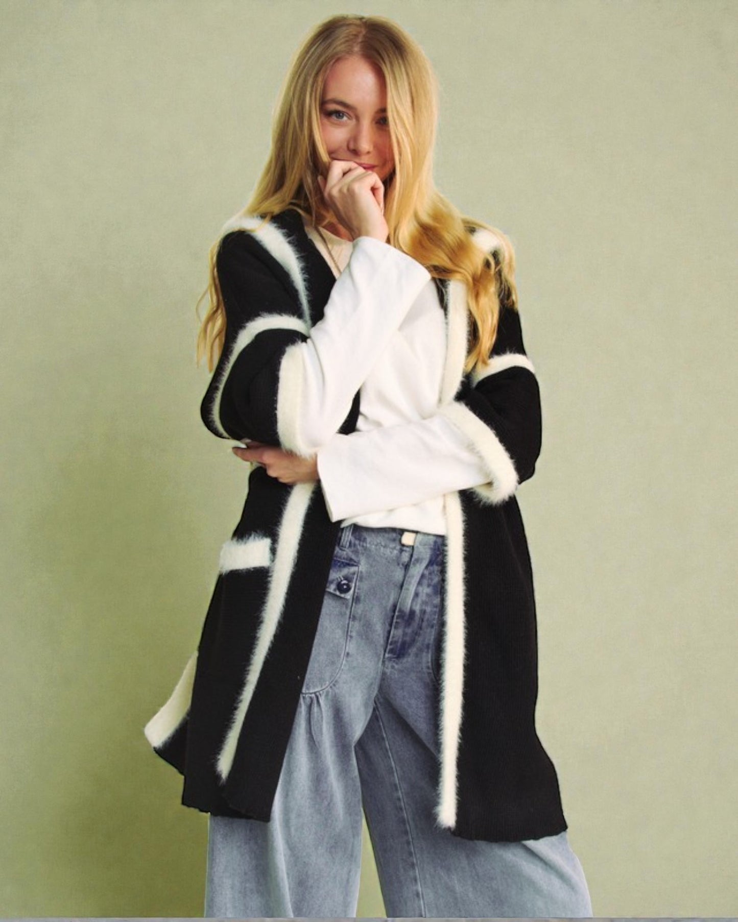 Woman wearing a black and white striped coat with fur trim on a plain background