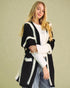 Woman wearing a black and white patterned cardigan against a beige background