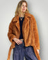 Woman wearing a brown teddy coat against a plain background