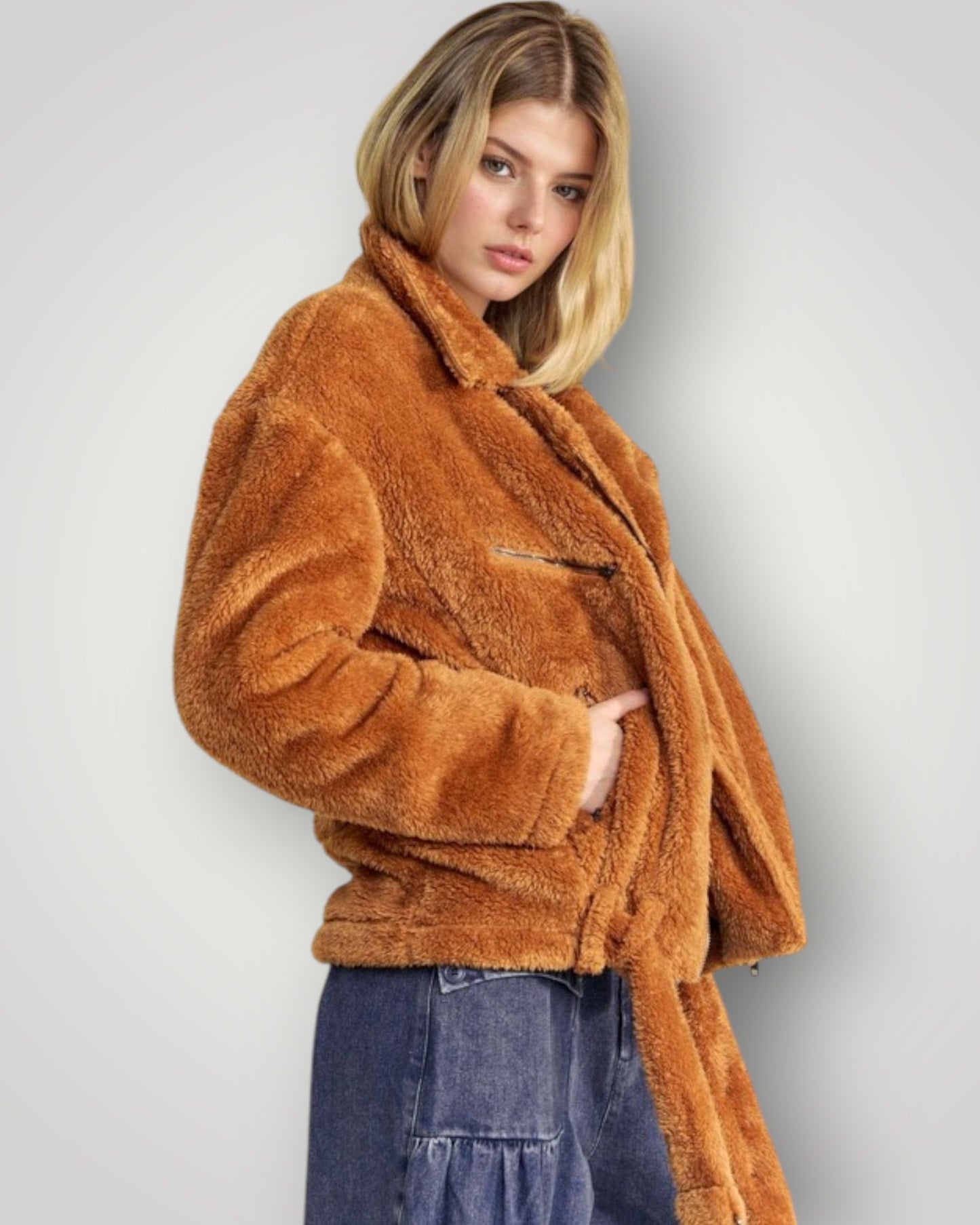 Woman wearing a brown faux fur coat against a plain background