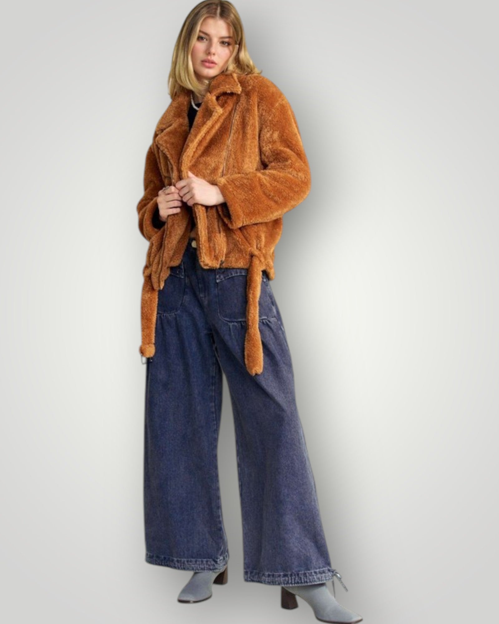 Woman wearing a brown fur coat and blue jeans on a plain background
