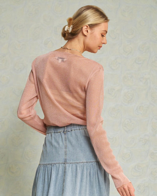 Woman wearing a pink sweater and denim skirt against a textured beige background