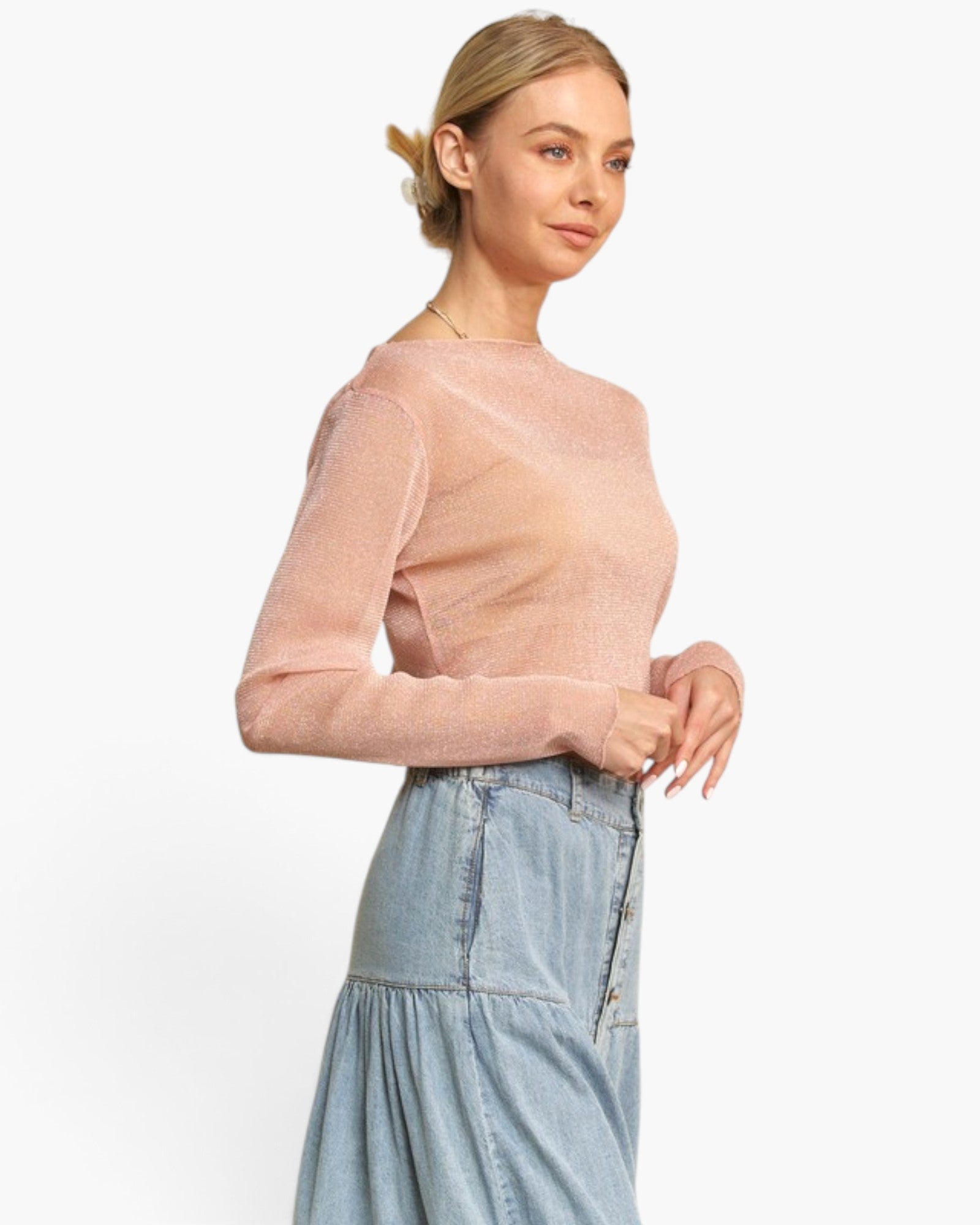 A woman wearing a light pink long-sleeve knit top and a light blue denim skirt, photographed against a clean white studio background.