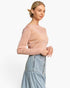 A woman wearing a light pink long-sleeve knit top and a light blue denim skirt, photographed against a clean white studio background.