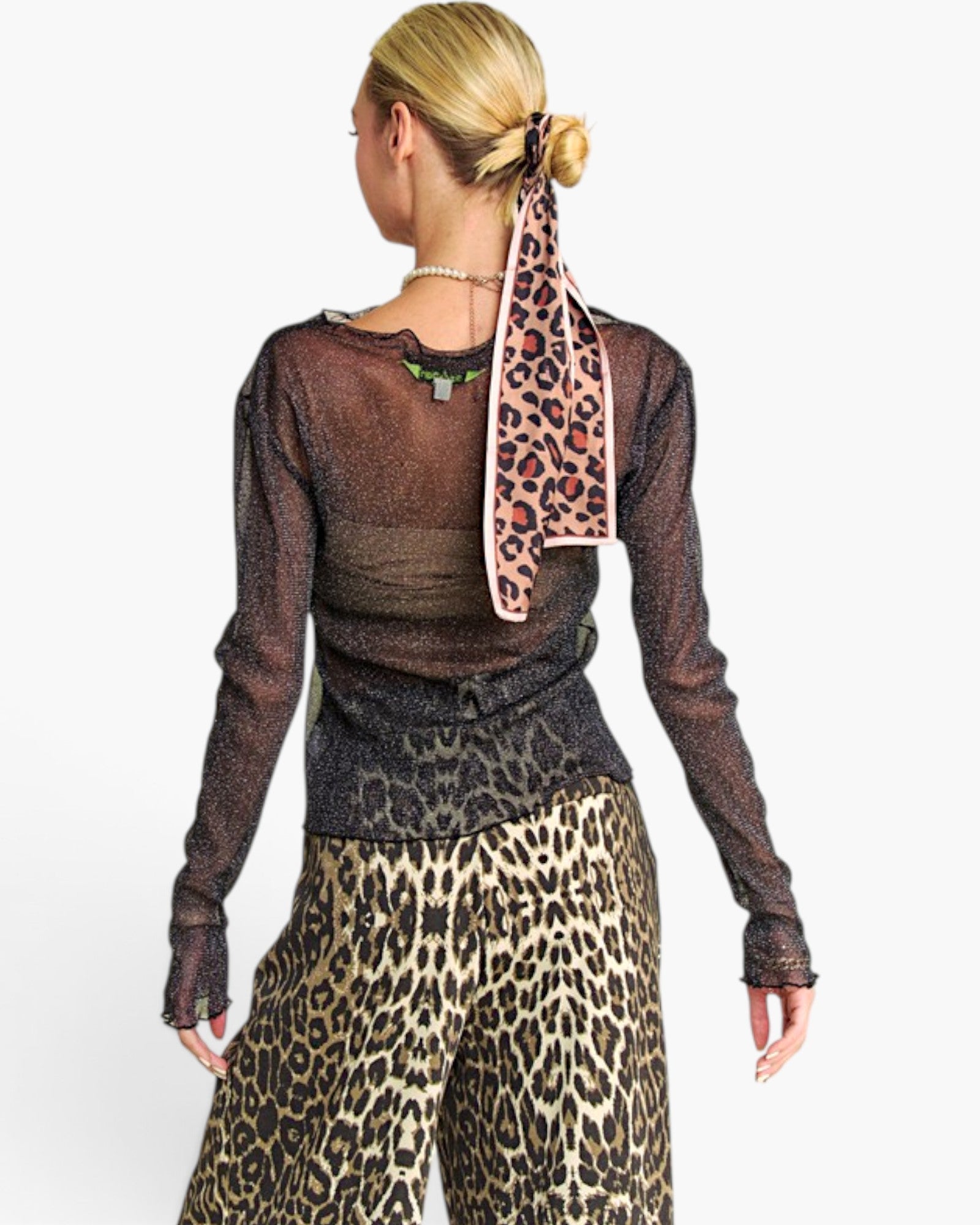 A woman shown from the back wearing a sheer dark brown long-sleeve top with a leopard-print pattern at the hem, paired with leopard-print pants, against a plain white studio background.