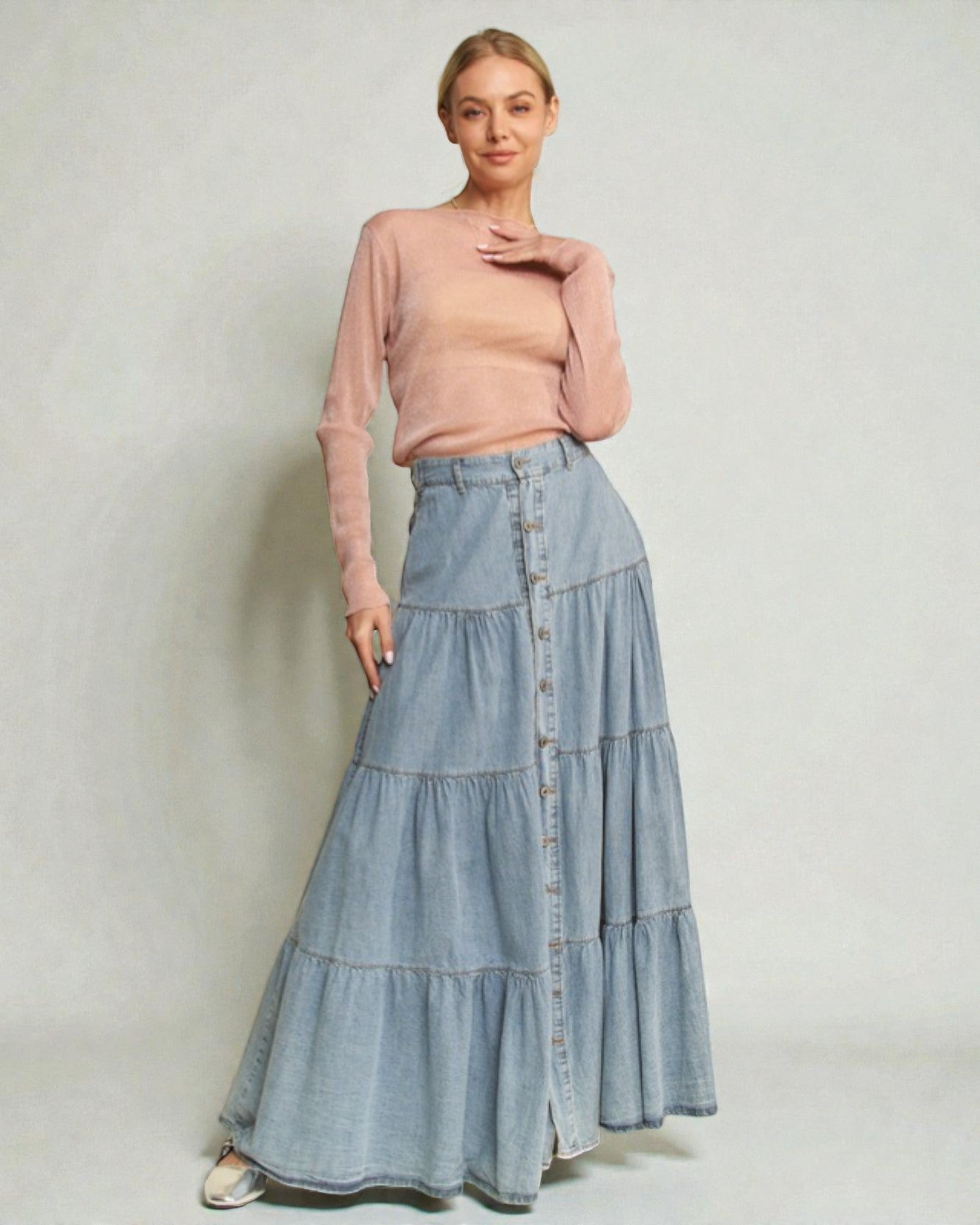 Woman wearing a pink top and denim skirt against a plain background