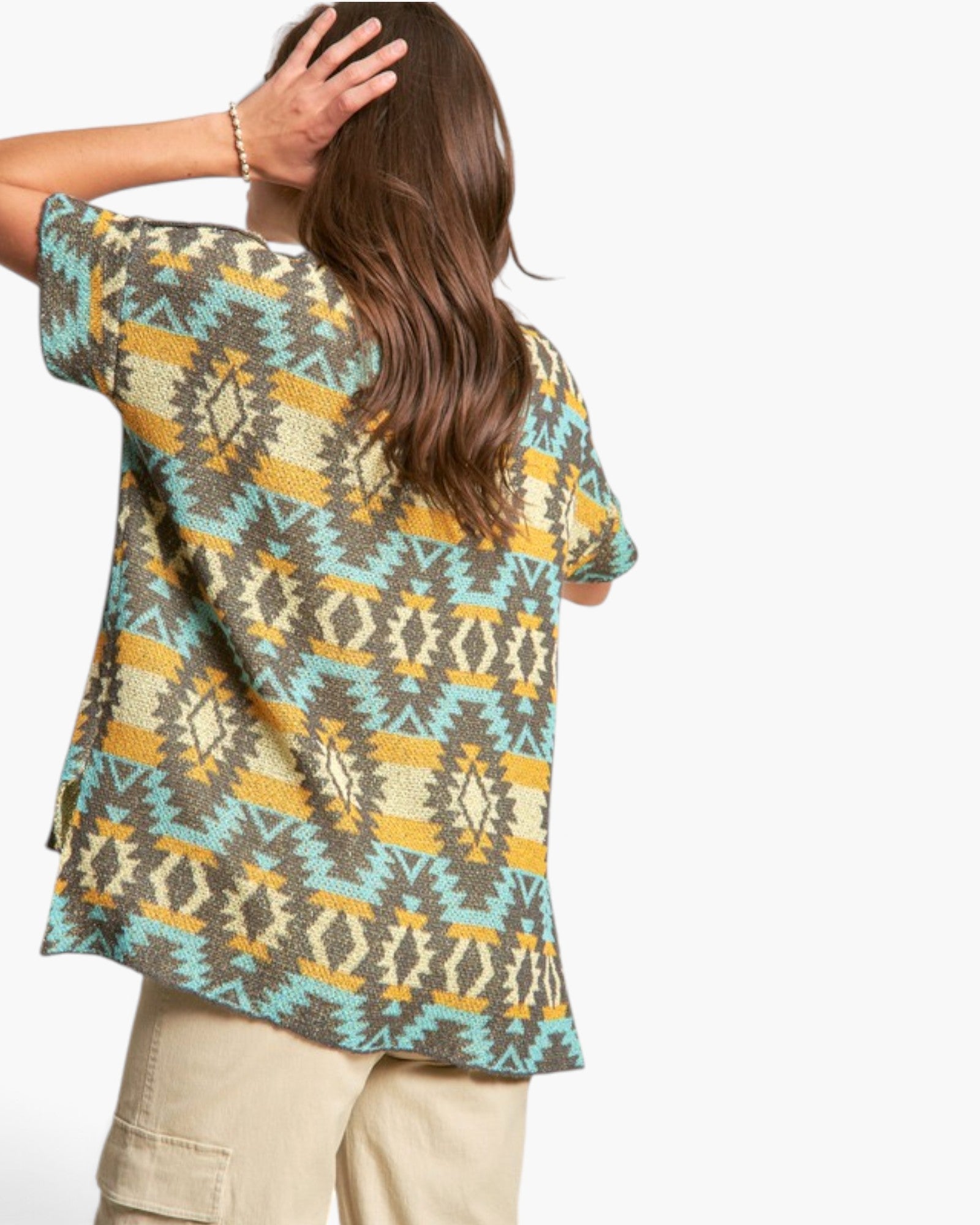 A woman shown from the back wearing a short-sleeve knit top with a colorful geometric Southwestern pattern in teal, mustard yellow, brown, and cream, paired with beige cargo pants against a plain white background.