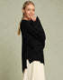 Woman wearing a black sweater over a white dress on a light green background