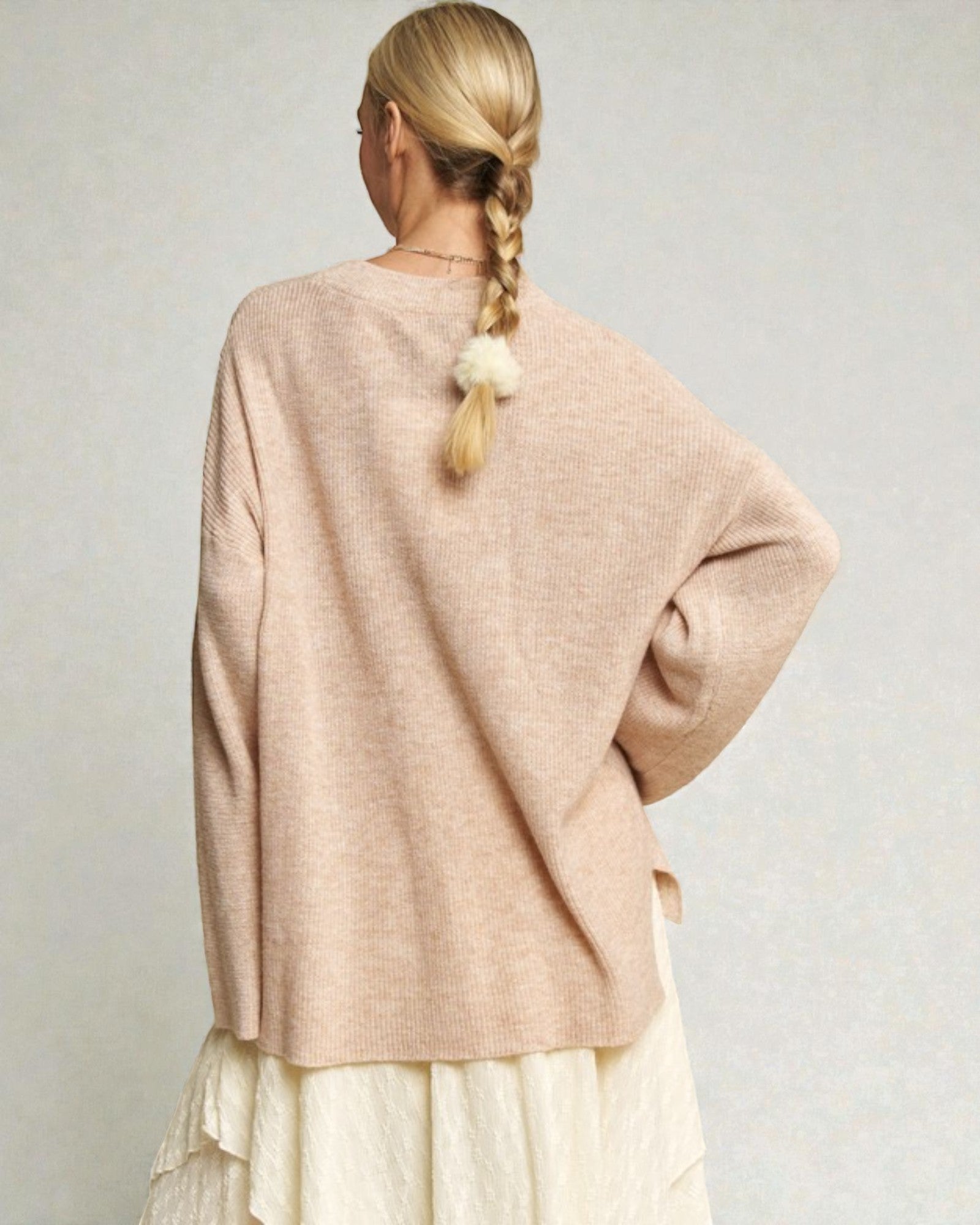 Person wearing a beige sweater with a plain background