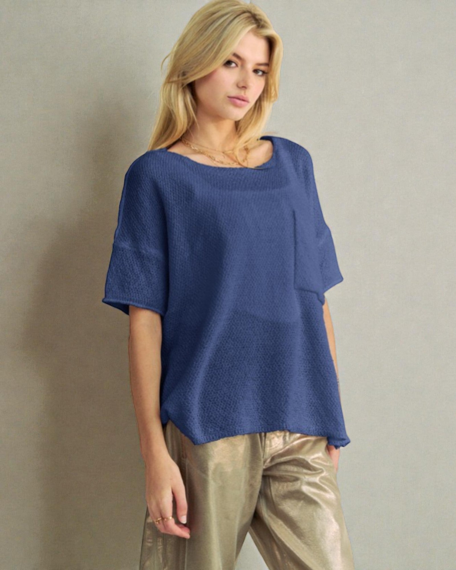 Woman wearing a blue top and beige pants against a plain background