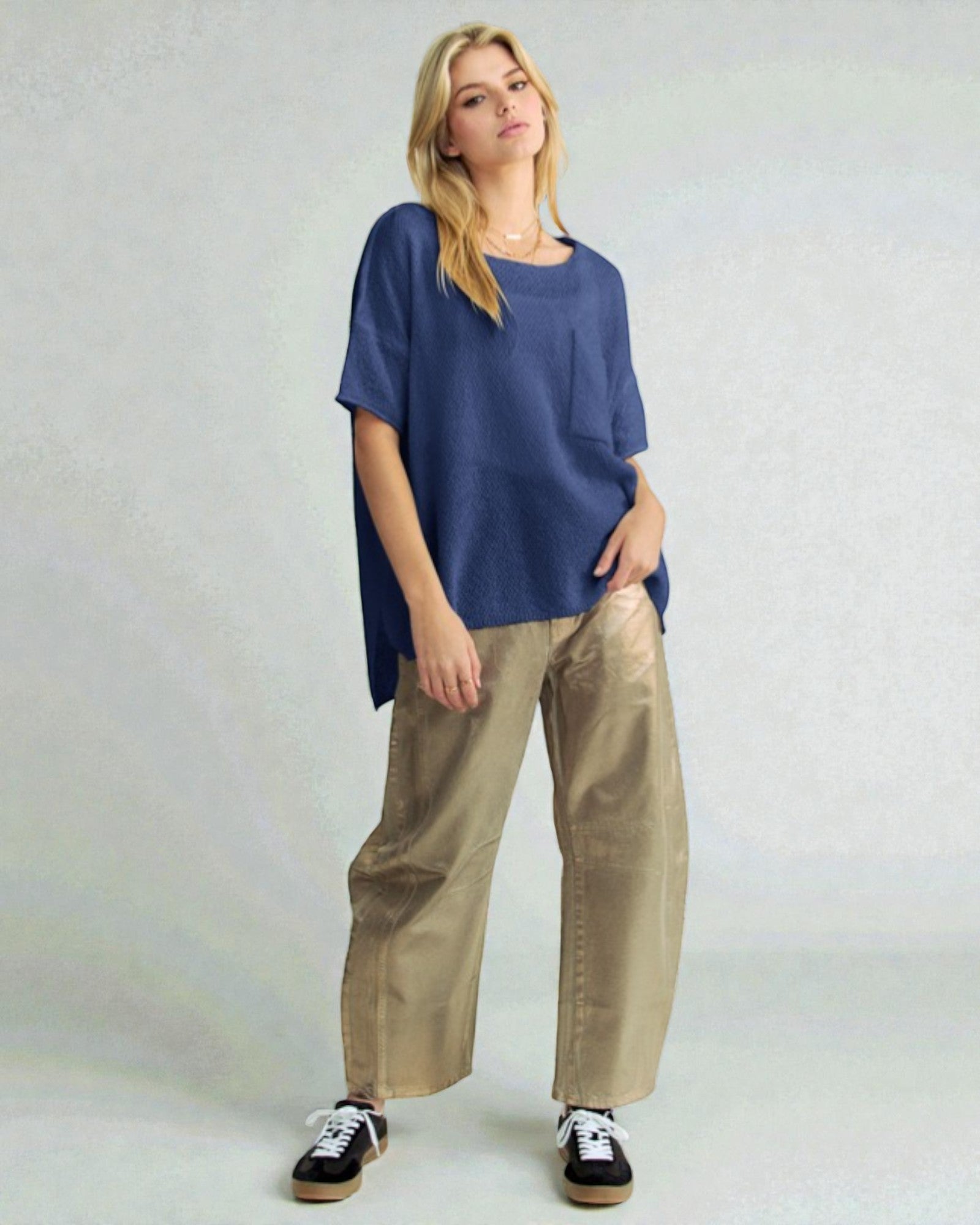 Woman wearing a blue top and beige pants on a plain background