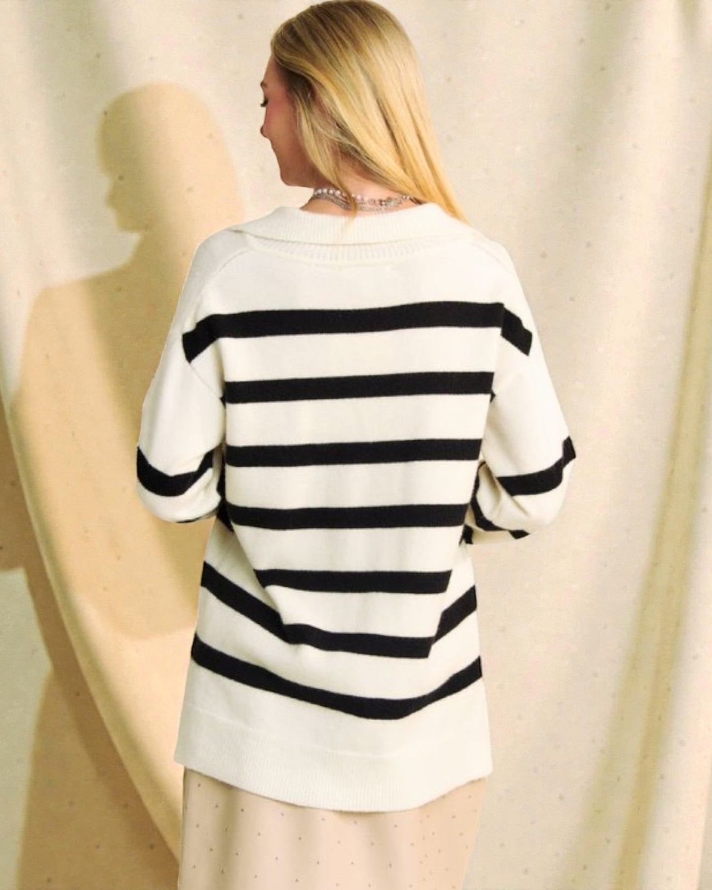 Person wearing a black and white striped sweater against a neutral background