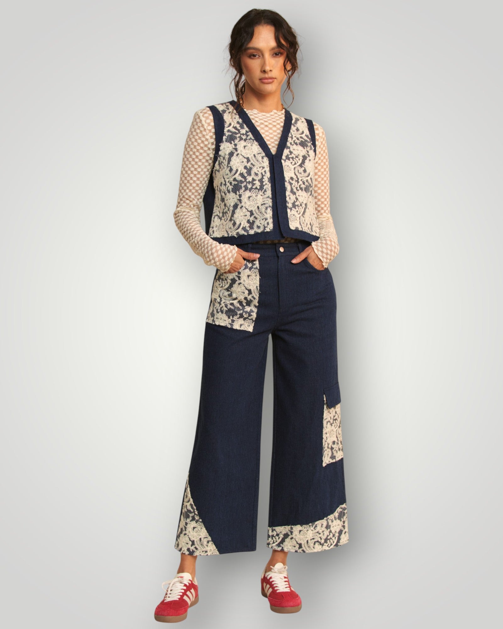 Woman wearing a floral top and navy wide-leg pants with a white background