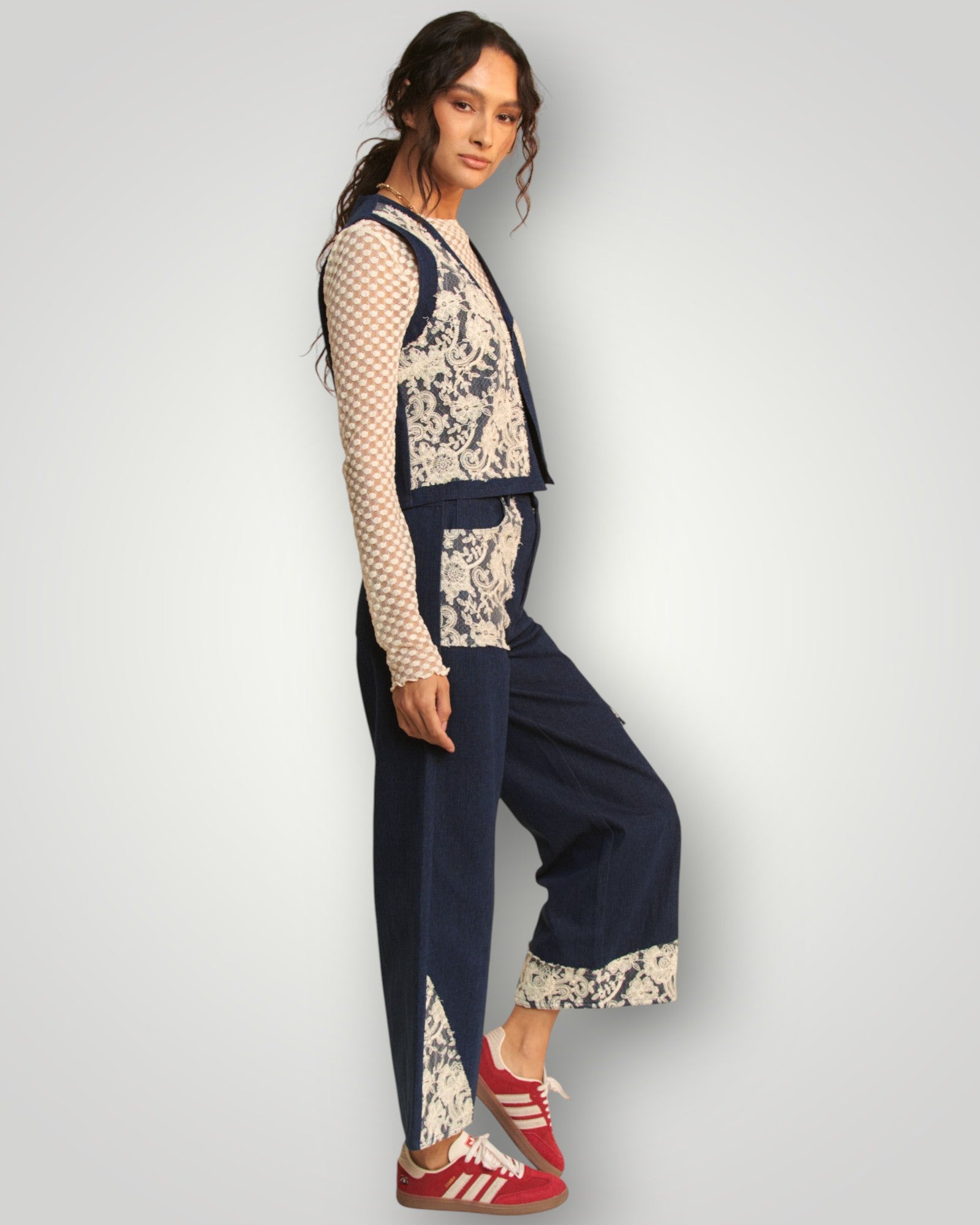 Woman wearing a navy blue and beige patterned outfit with red sneakers on a light gray background