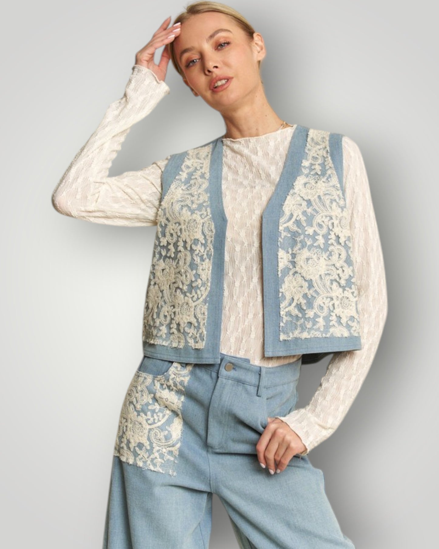 Woman wearing a stylish outfit with a floral patterned top and blue pants against a plain background