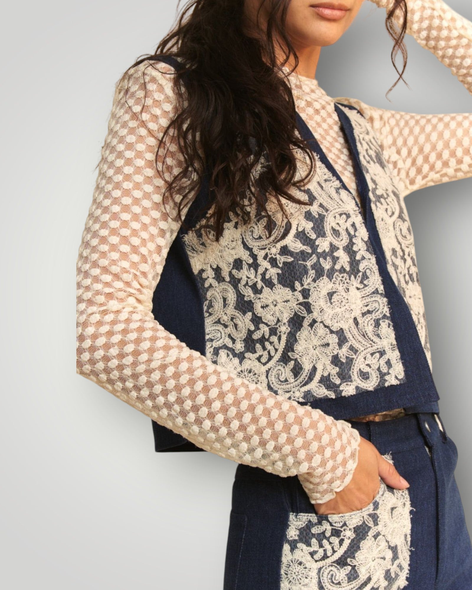 Woman wearing a navy blue and white patterned outfit with sheer sleeves against a gray background