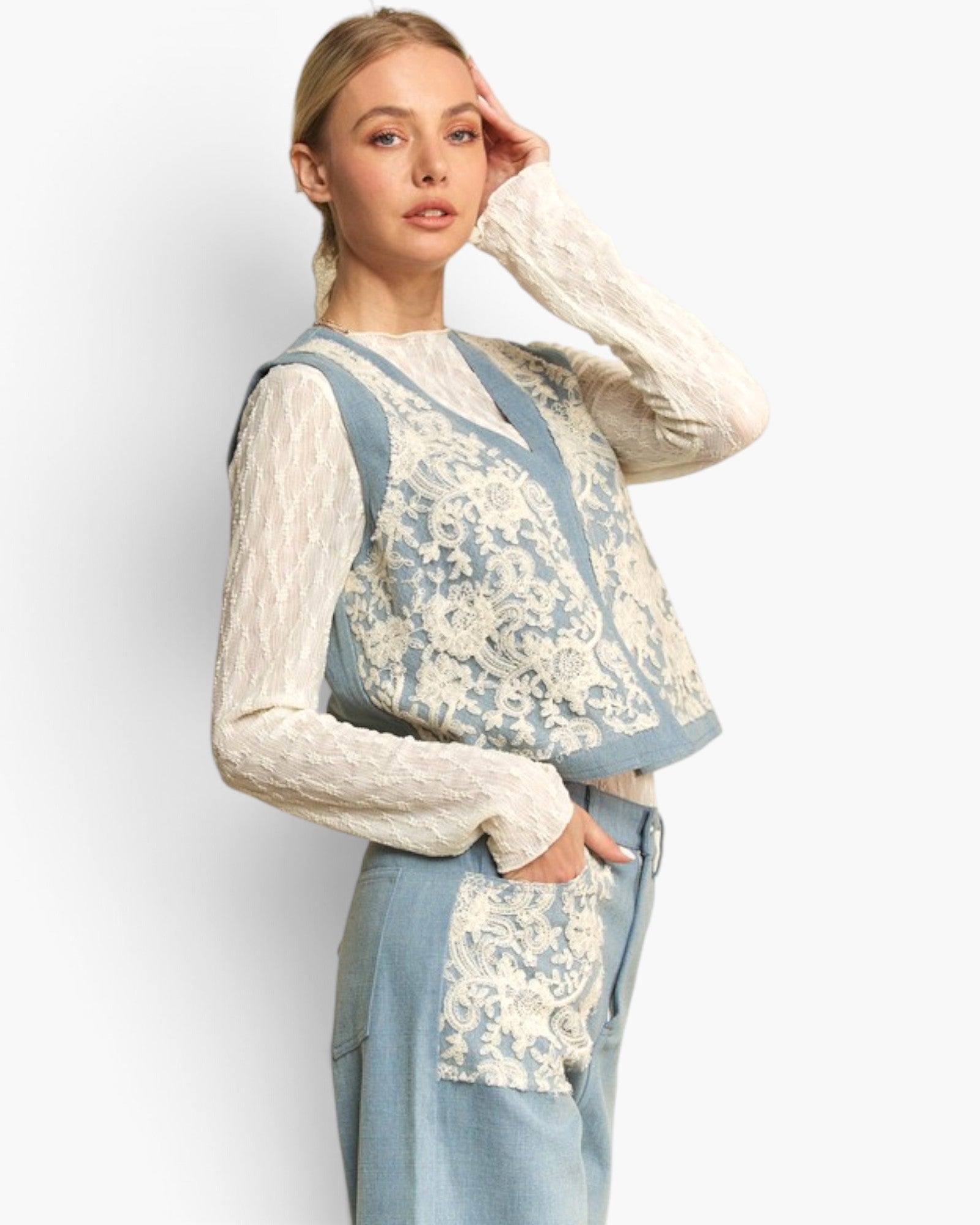 A woman models a light blue denim vest with cream lace overlay and matching light blue denim trousers against a plain light gray background.