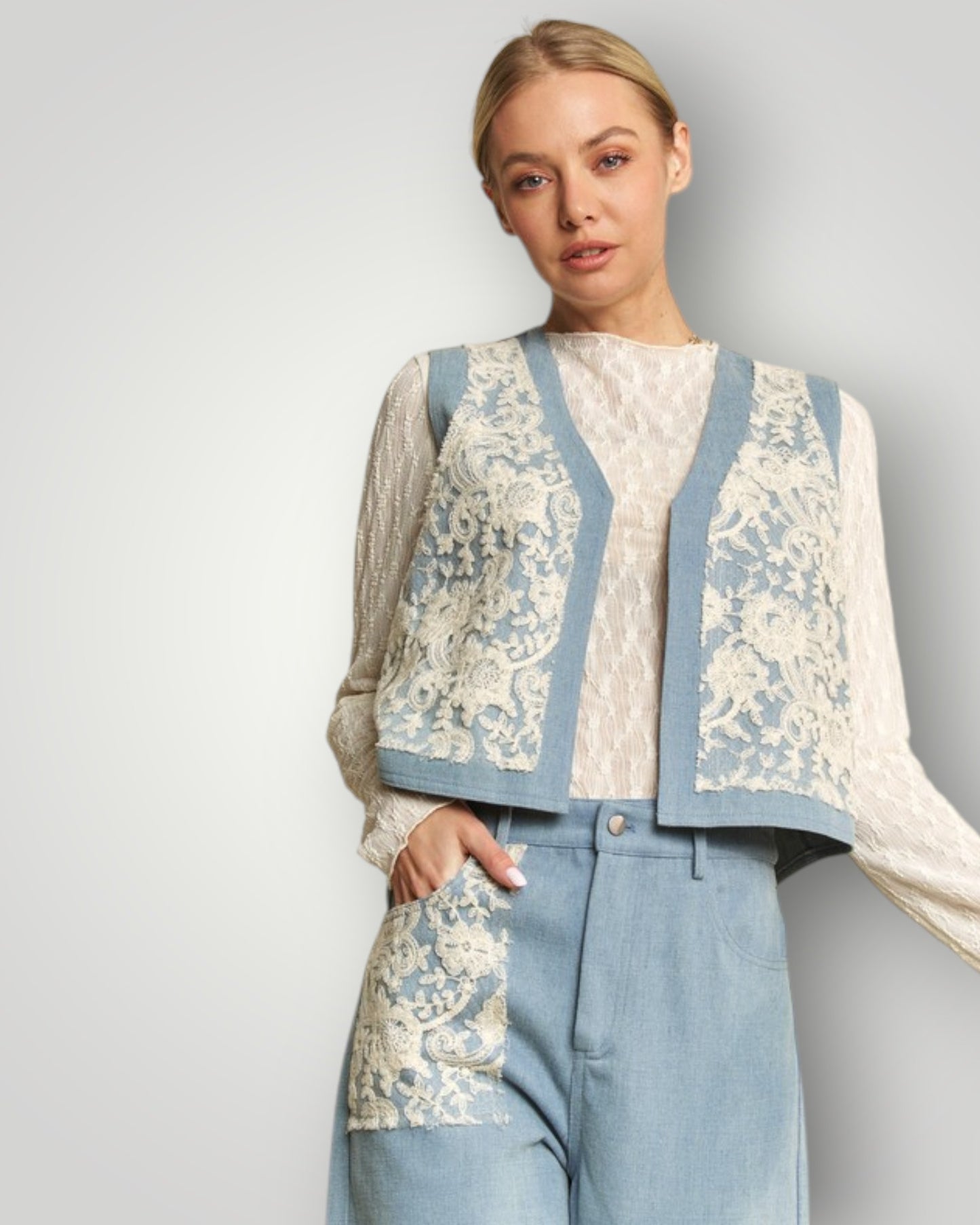 Woman wearing a floral-patterned cardigan over a white blouse with blue pants on a plain background