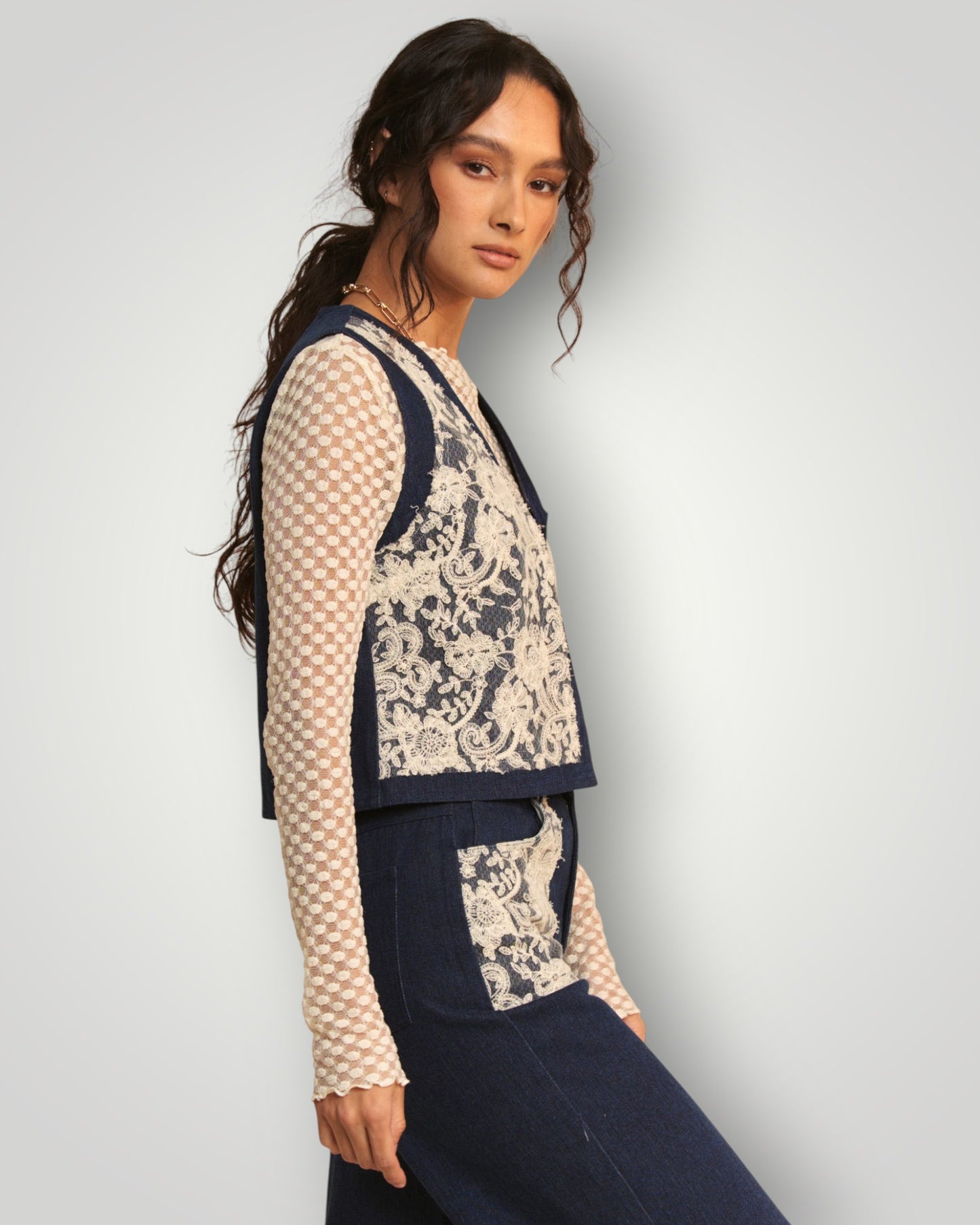 Woman wearing a patterned outfit with a lace detail on a plain background