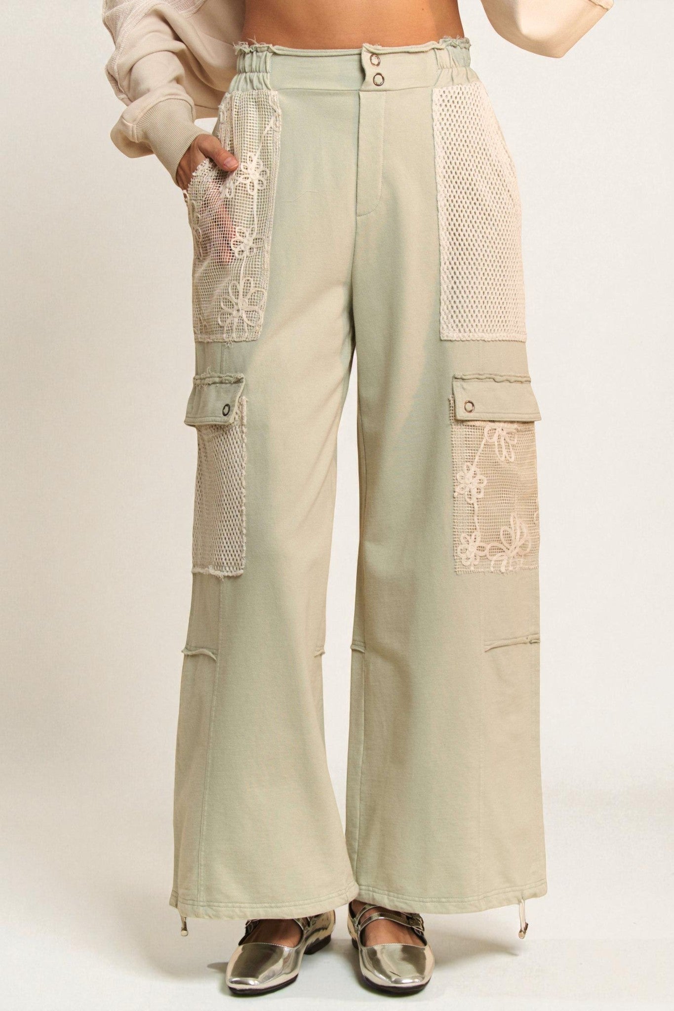 Light green cargo pants with lace detailing on a plain background