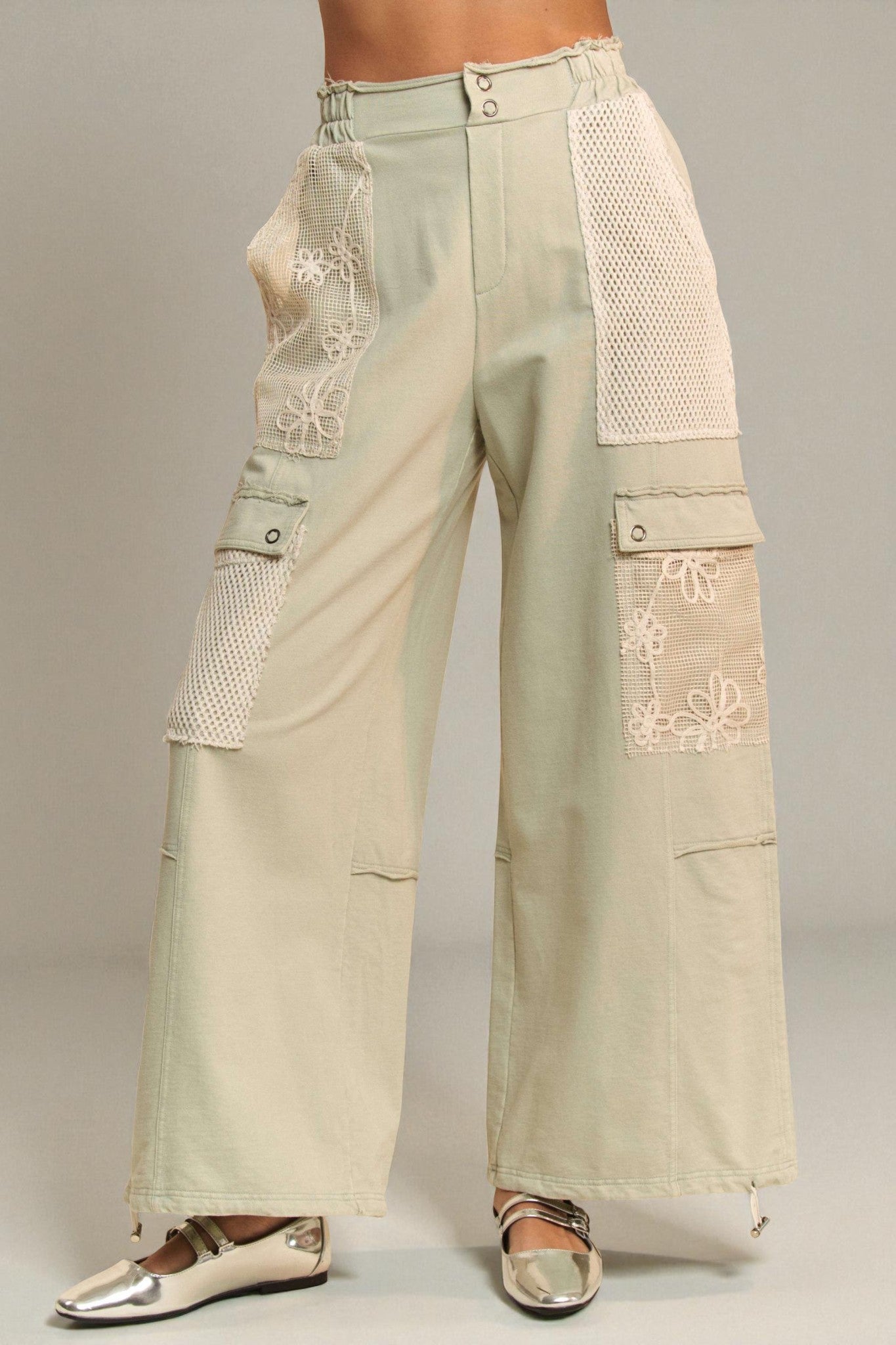 Beige pants with floral embroidery on a plain background