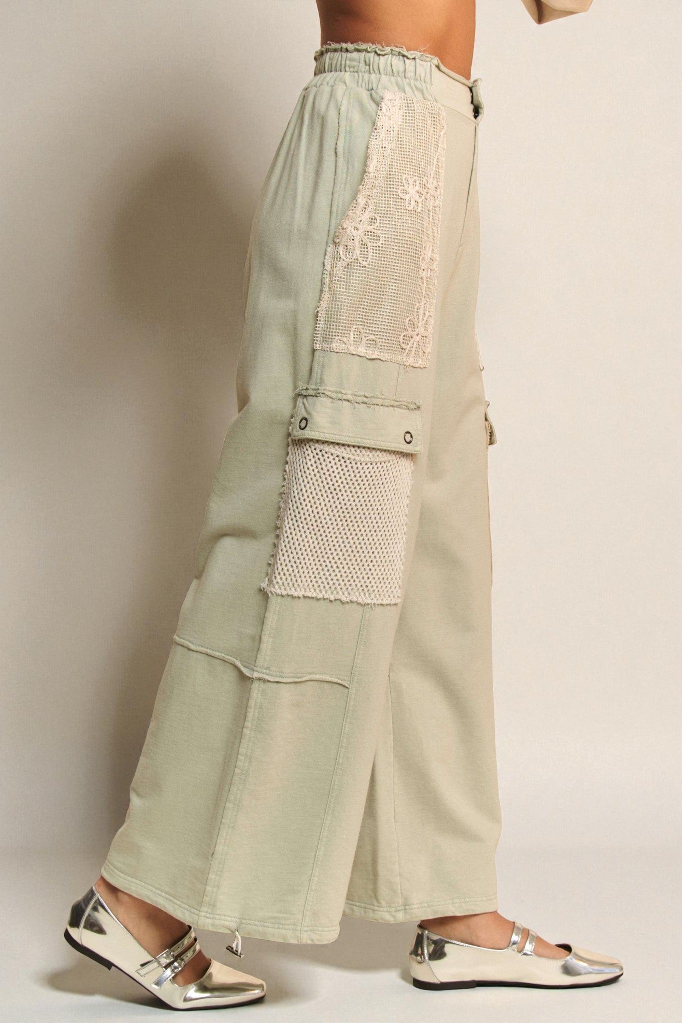 Light green pants with lace detailing on a plain background