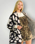 Woman wearing a patterned coat with a leopard print design on a plain background