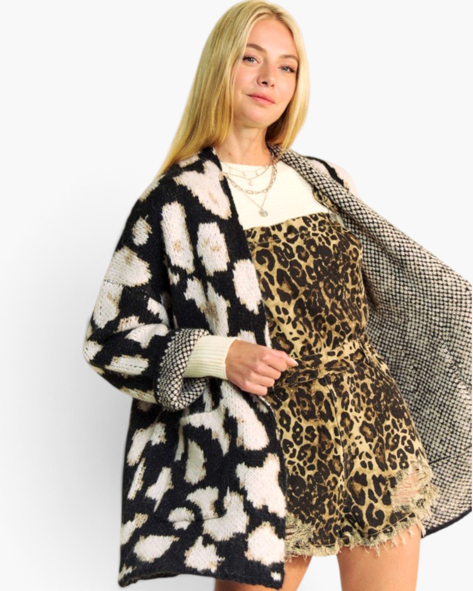 A woman modeling a black and white ikat pattern knit cardigan layered over a leopard print dress, against a plain white studio background.