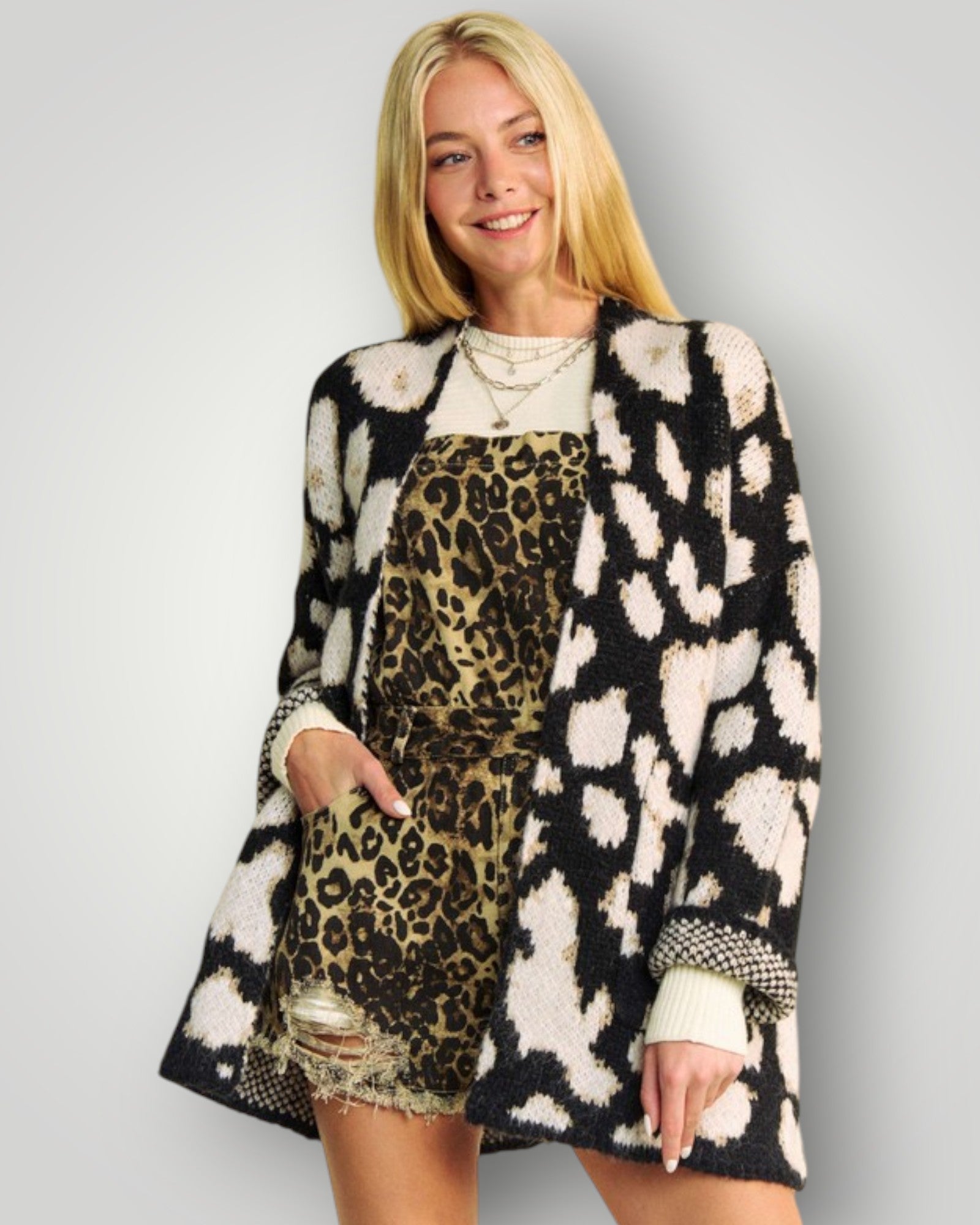 Woman wearing a patterned coat over a leopard print dress on a plain background