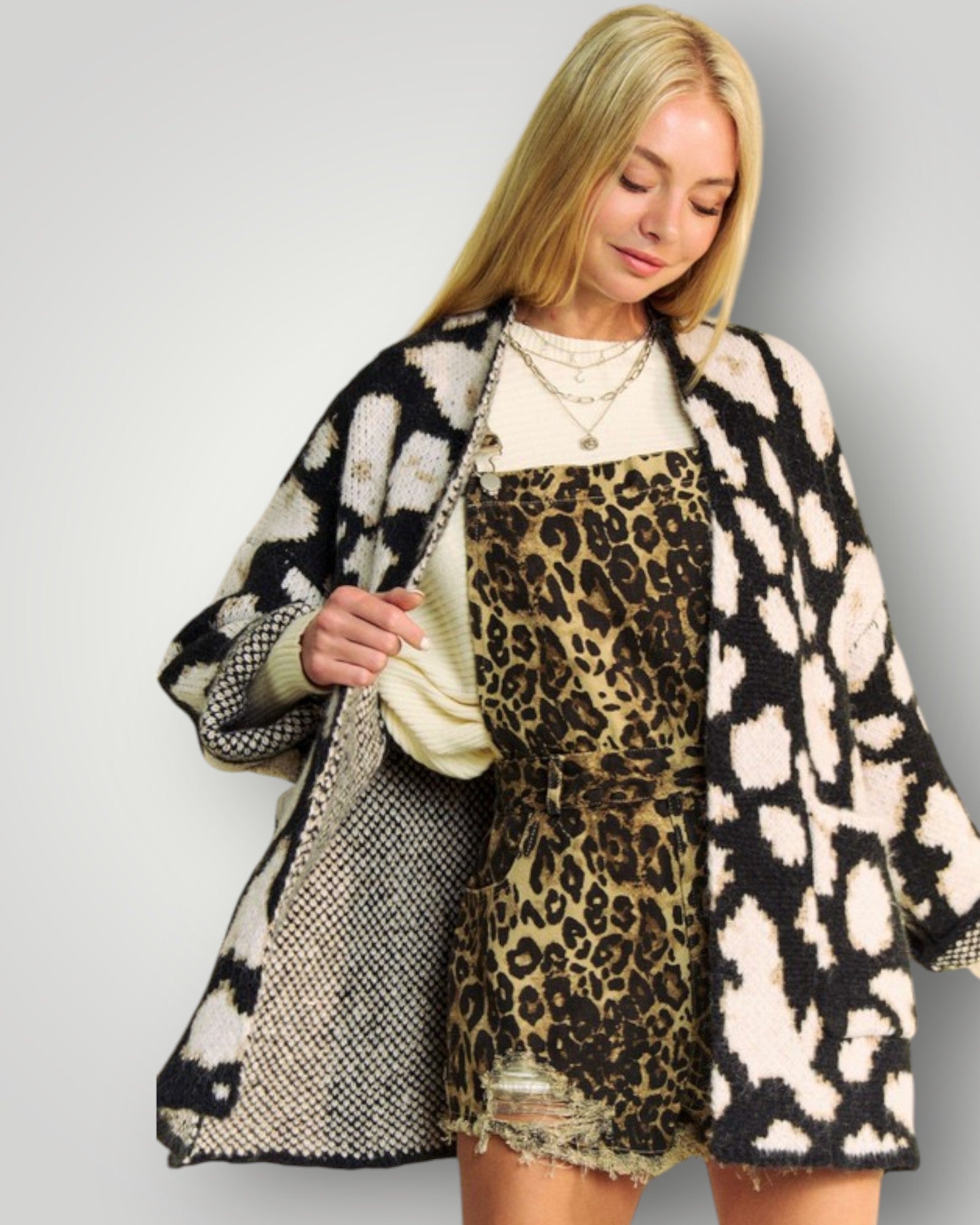 Woman wearing a patterned coat over a leopard print dress on a plain background