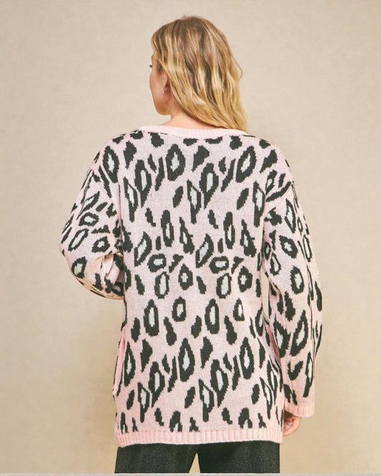 Person wearing a pink sweater with black leopard print pattern on a beige background