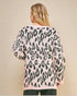 Person wearing a pink sweater with black leopard print pattern on a beige background