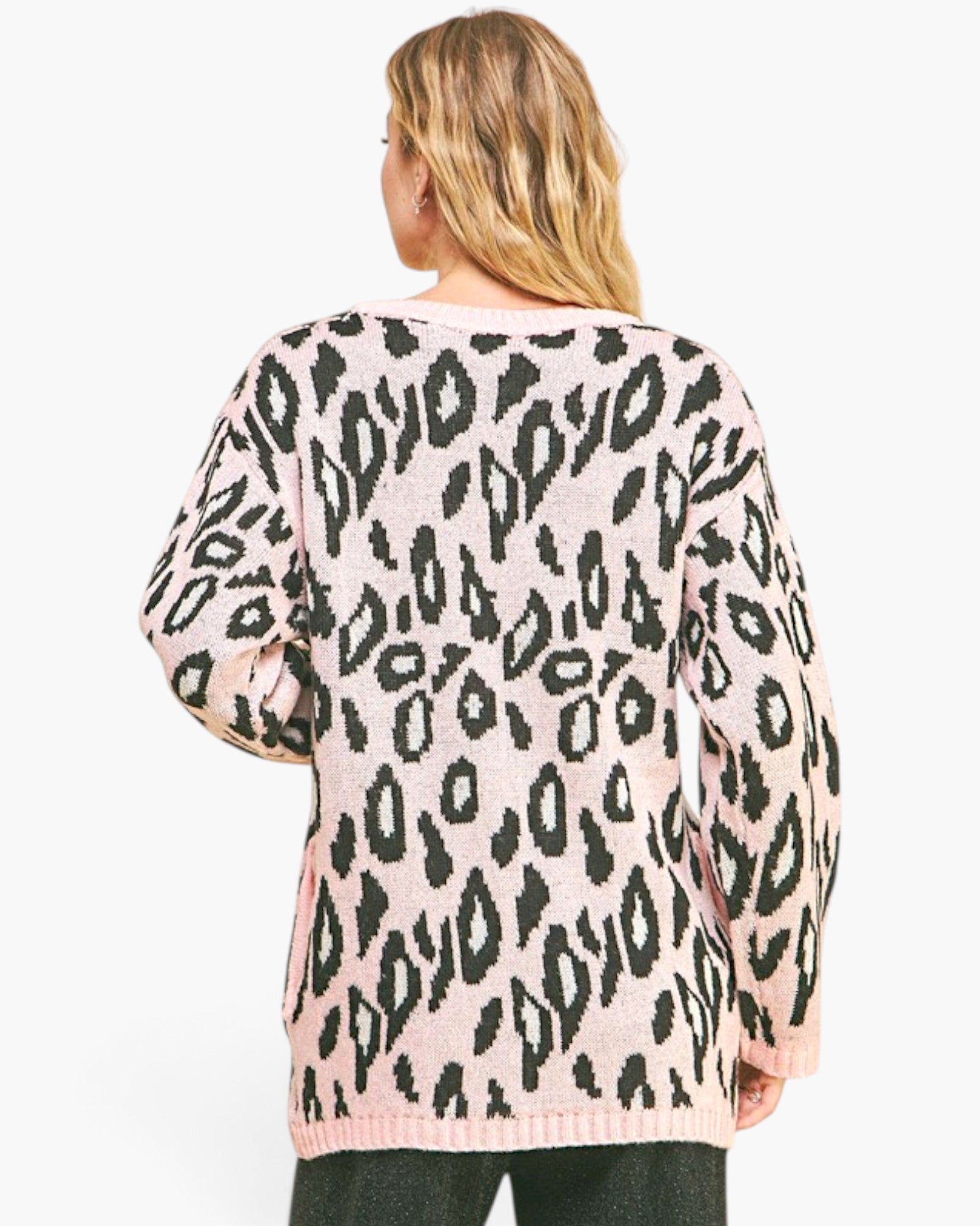 A woman viewed from the back wearing a pink knit sweater with a black leopard print pattern, set against a plain white background.