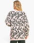A woman viewed from the back wearing a pink knit sweater with a black leopard print pattern, set against a plain white background.