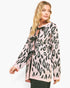 A woman modeling a pink knit cardigan with a black leopard print pattern and black ribbon tie details at the neckline and front, photographed against a plain white studio background.