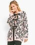 A woman wearing a pink and black leopard print knit cardigan with black ribbon laces, paired with black pants, against a plain white studio background.