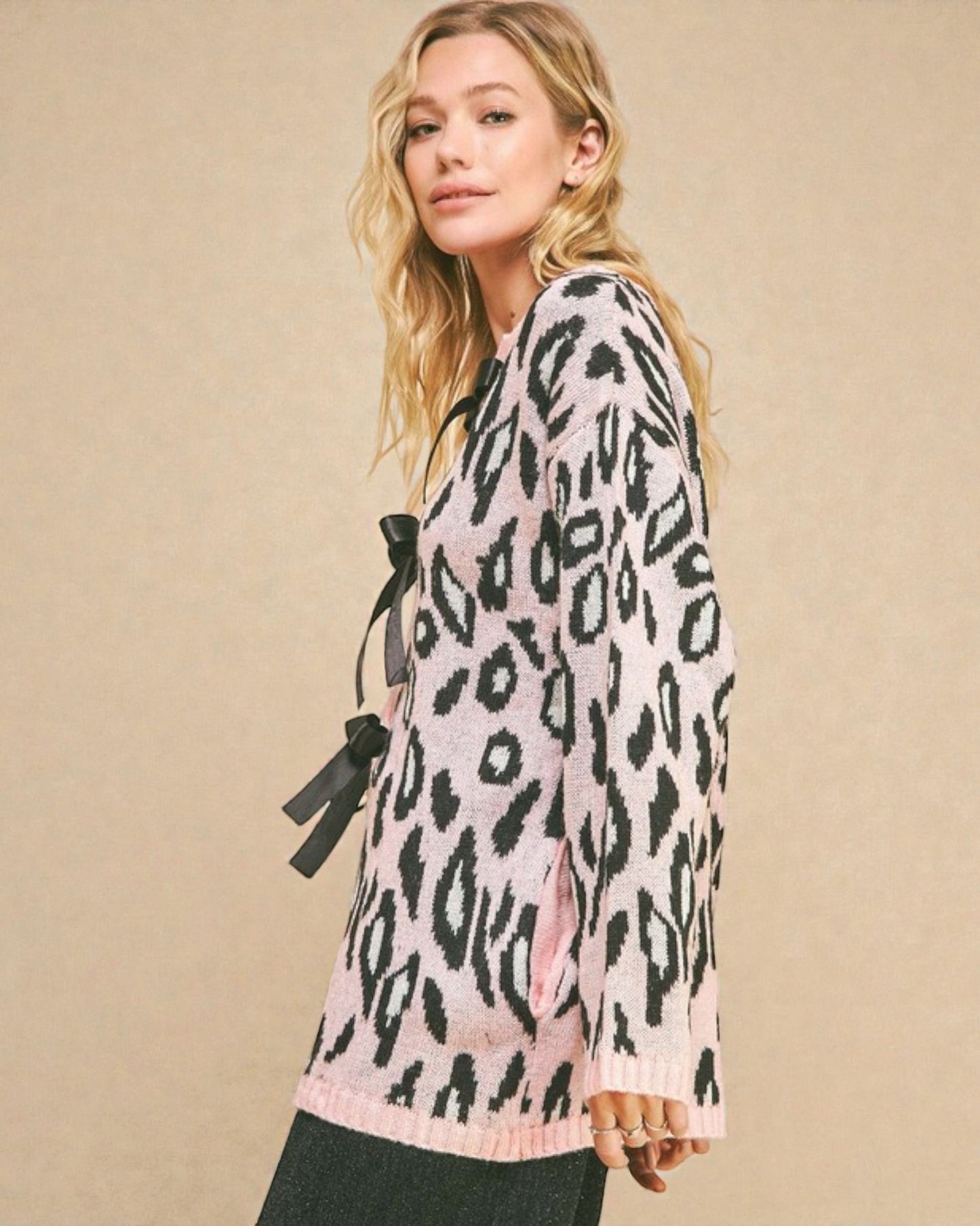 Woman wearing a pink sweater with black leopard print against a beige background