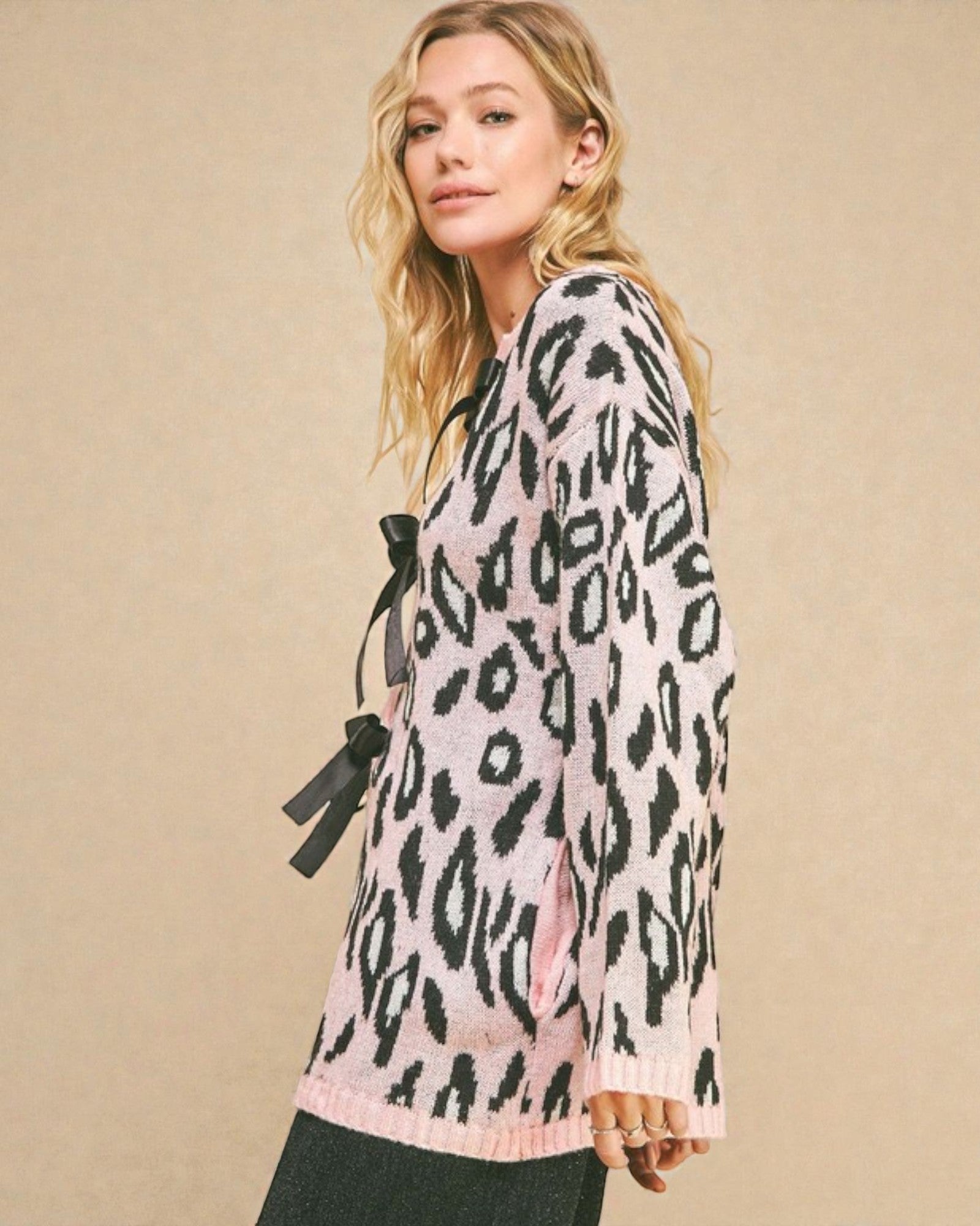 Woman wearing a pink sweater with black leopard print against a beige background
