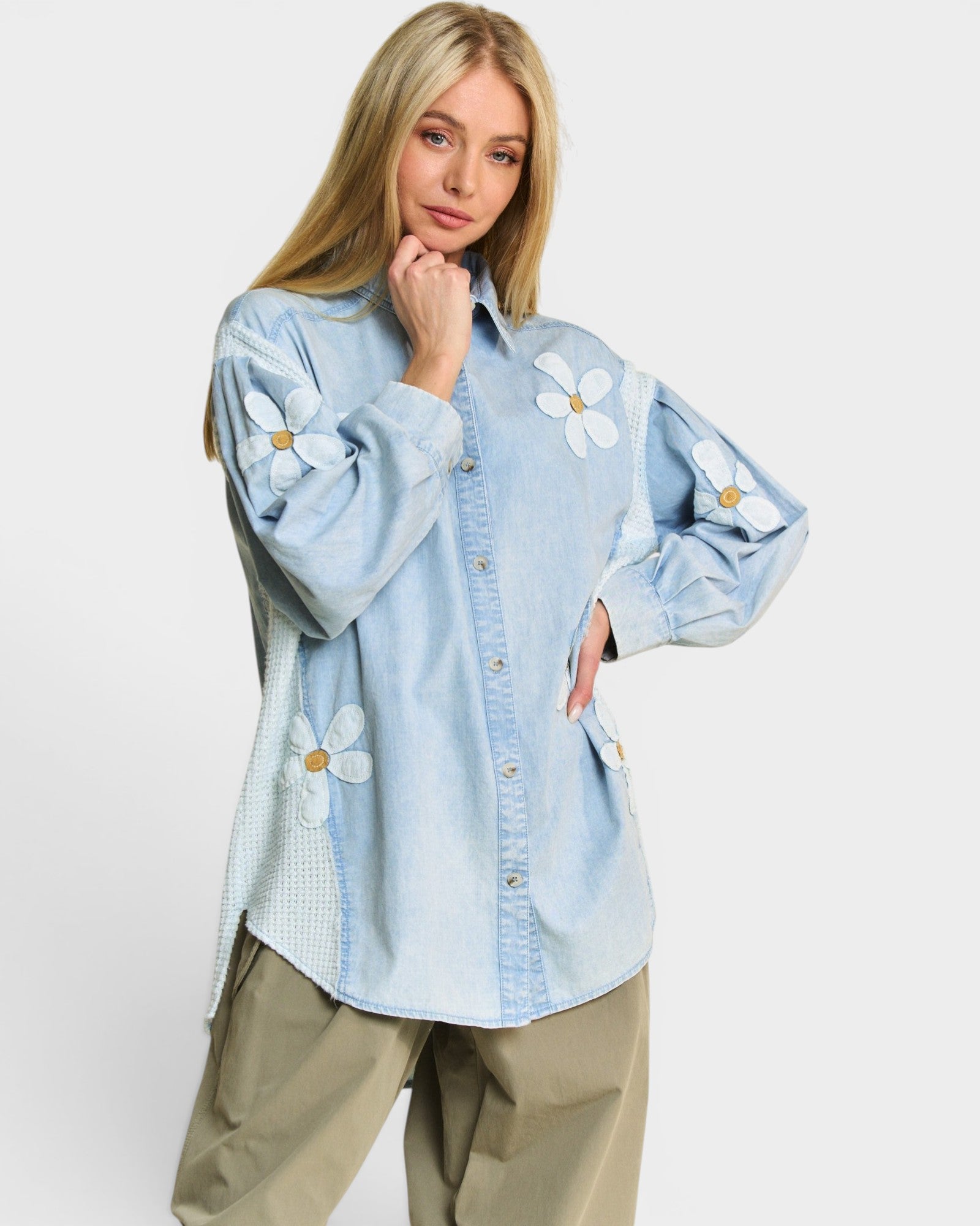 Woman wearing a light blue denim shirt with floral patterns on a white background