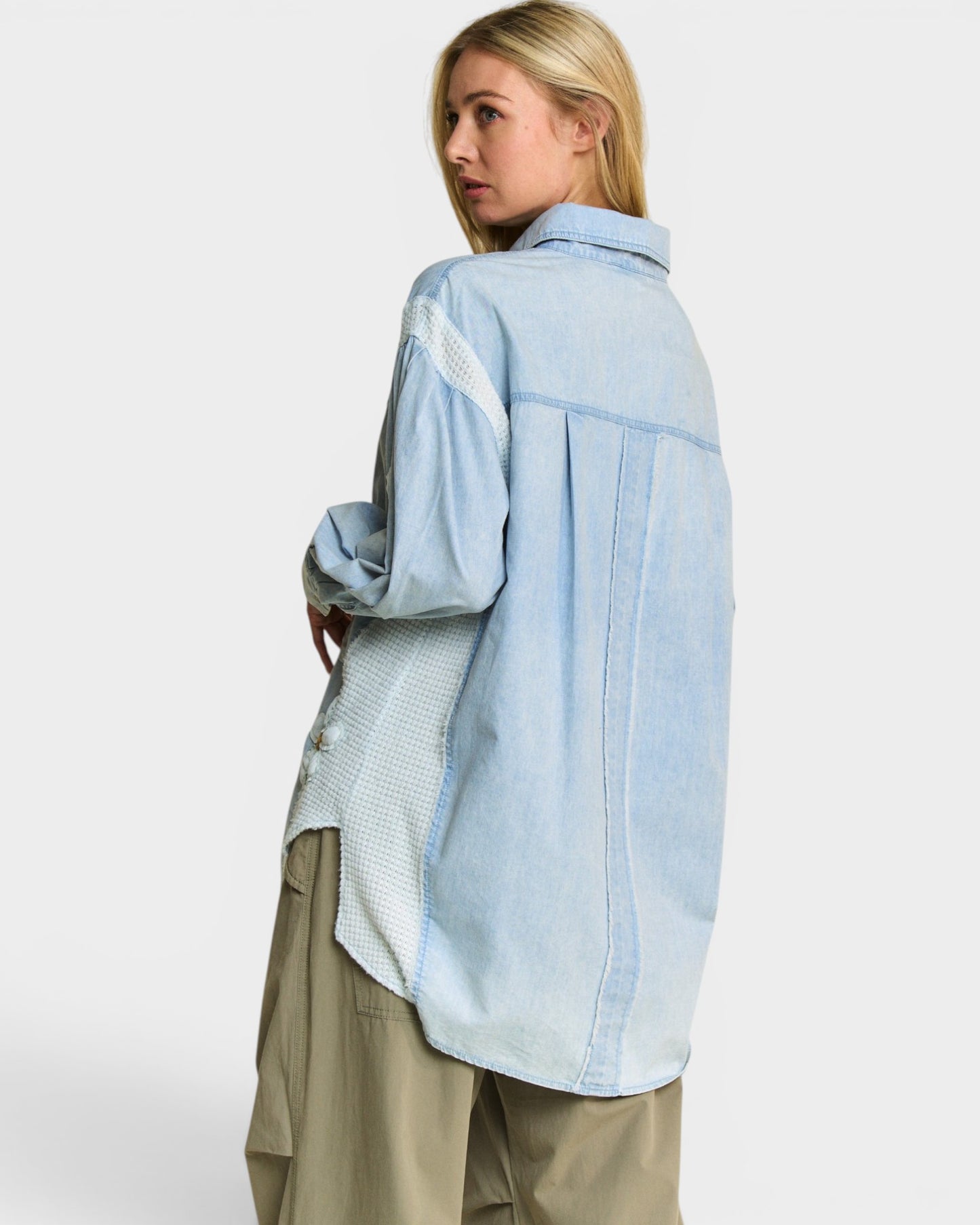 Woman wearing a light blue denim jacket on a white background