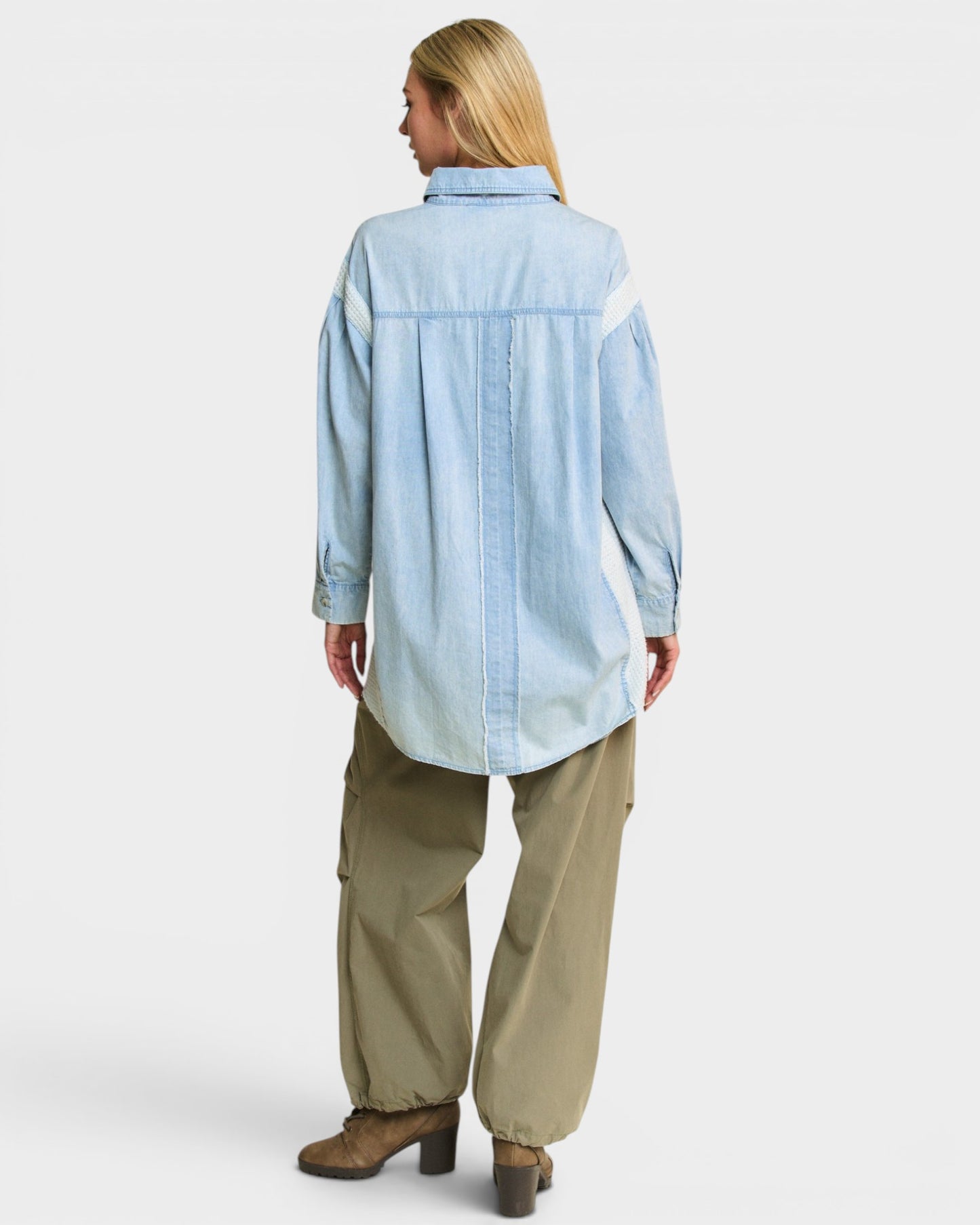 Woman wearing a light blue shirt and beige pants on a white background