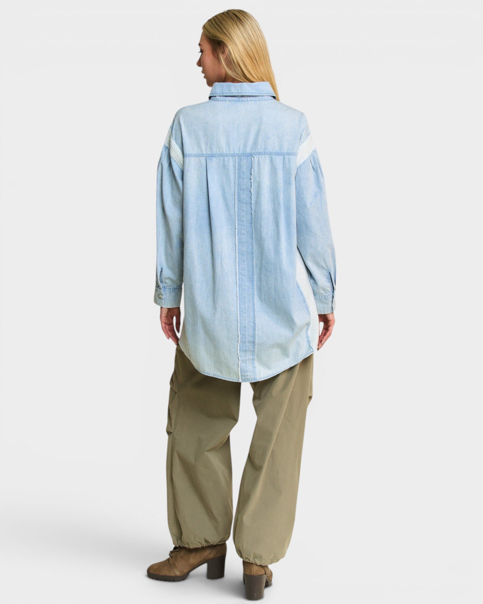 Woman wearing a light blue shirt and beige pants on a white background