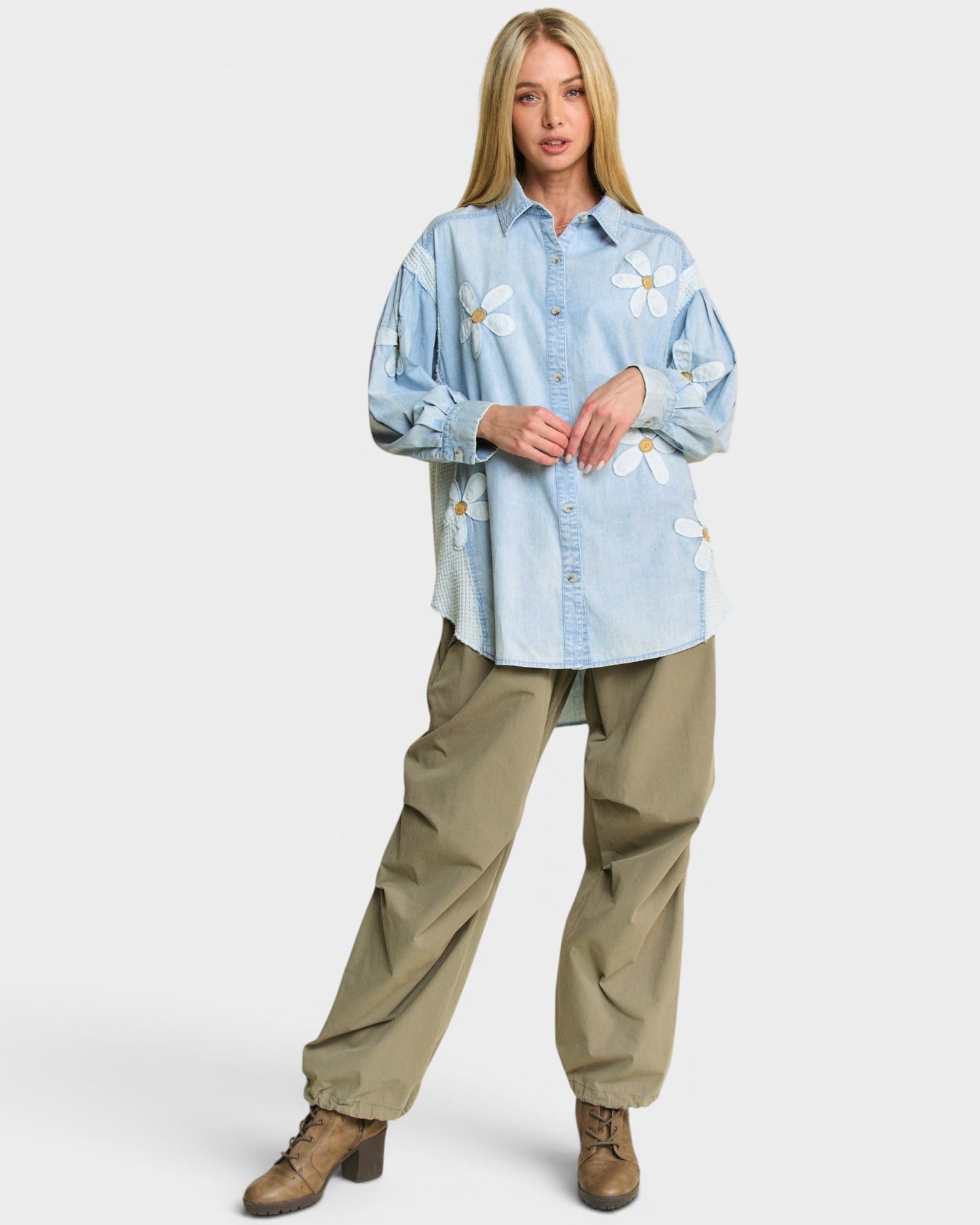 Woman wearing a light blue floral shirt and beige pants on a white background
