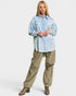 Woman wearing a light blue floral shirt and beige pants on a white background