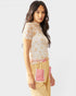 Woman wearing a floral top and checkered pants with pink accents on a white background